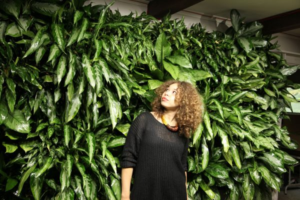 A woman admires a green living wall illuminated by a LiveWall Norb LED light.