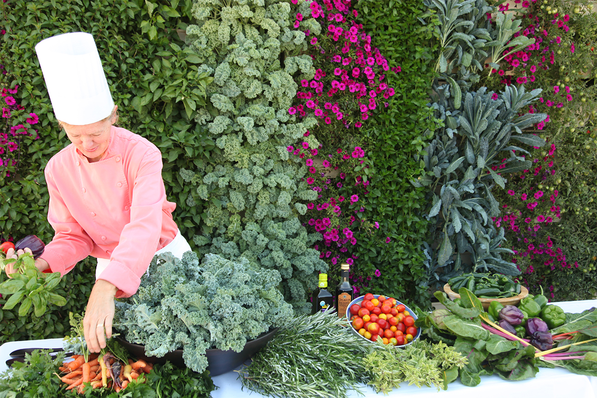 Culinary instructor arranges harvest from food wall.