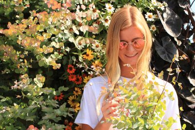 Woman in sunglasses in front of a colorful annual LiveWall with eucalyptus and zinnias.