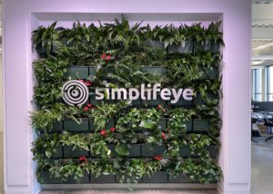 The logo and text of Simplifeye nestled in the center of a lush living wall
