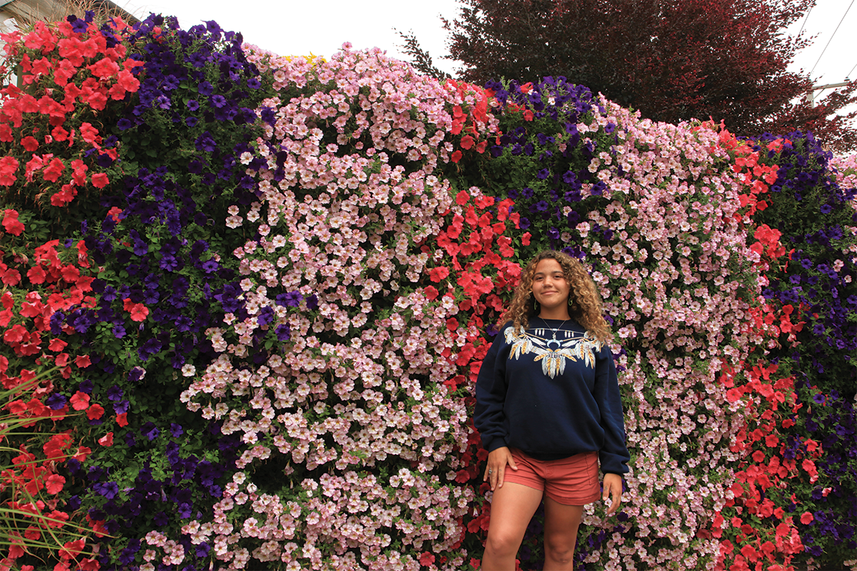 Woman standing in front of a living wall filled with pink, red, and dark violet annuals